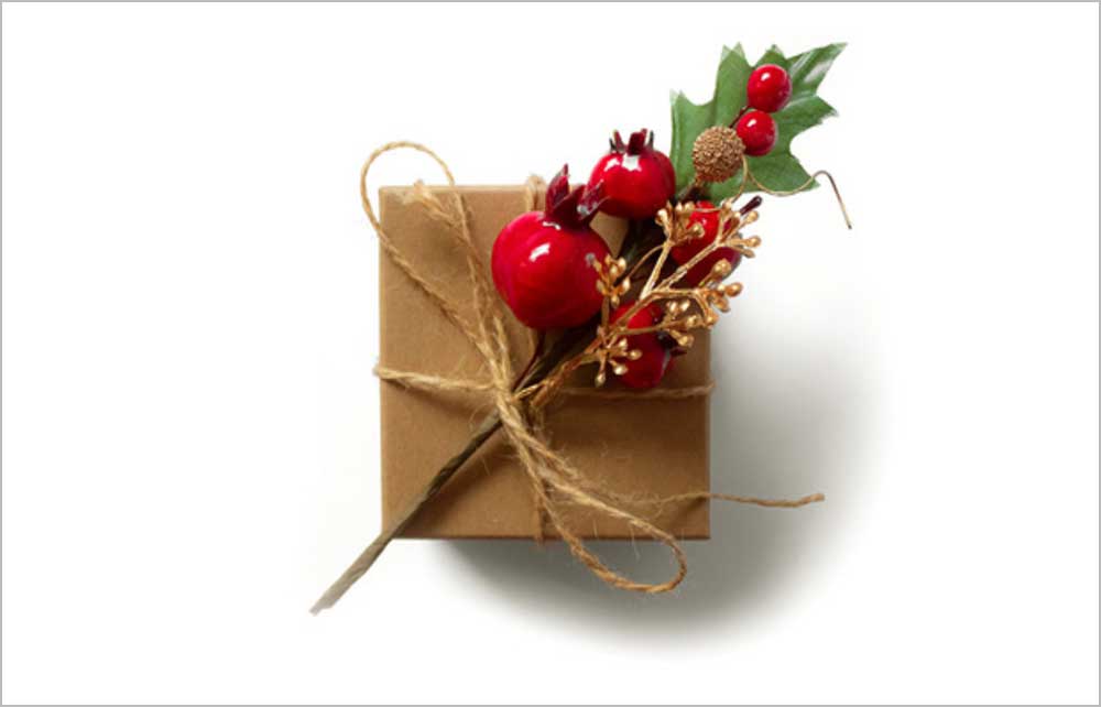 Ein Geschenk, schön eingepackt mit einem Zweig mit kleinen roten Äpfeln dran.